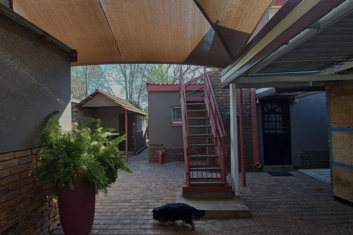 Rear courtyard area featuring brick paving, a shade sail covering, and an external metal staircase leading to an upper level.