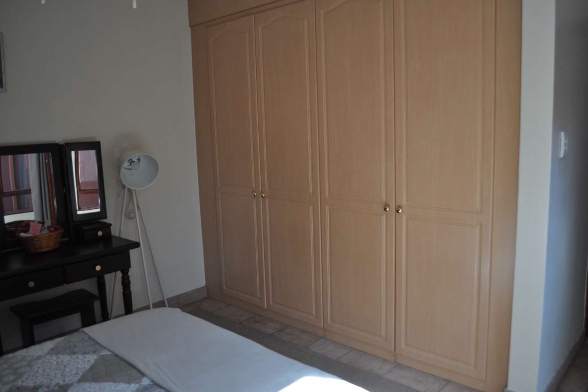 A bedroom featuring light wood-toned built-in cupboards providing ample storage space.