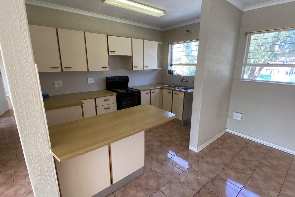 A functional kitchen featuring laminate countertops, built-in cabinetry, a double basin sink, and tiled flooring, offering a clean and practical layout.