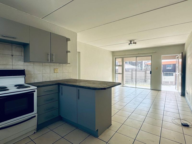 Open-plan kitchen and living area featuring tiled flooring, built-in cabinetry, and direct access to an outdoor patio through sliding glass doors.