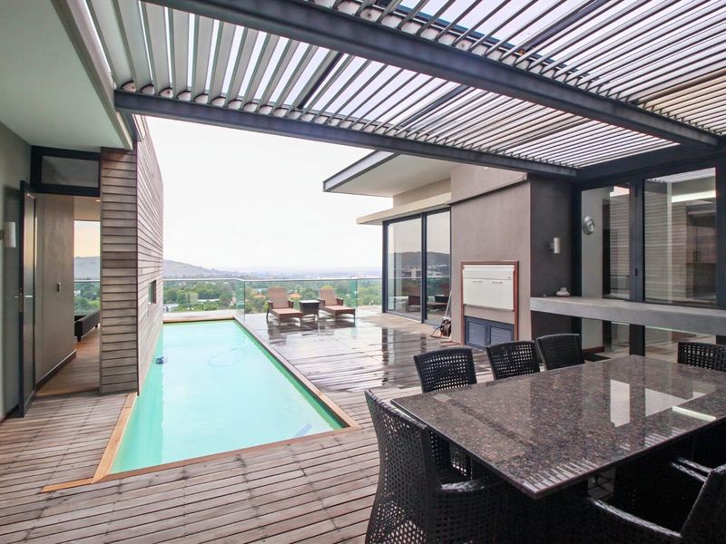 Spacious penthouse terrace featuring a private lap pool, integrated louvered roof system, built-in outdoor kitchen counter, and expansive panoramic views.