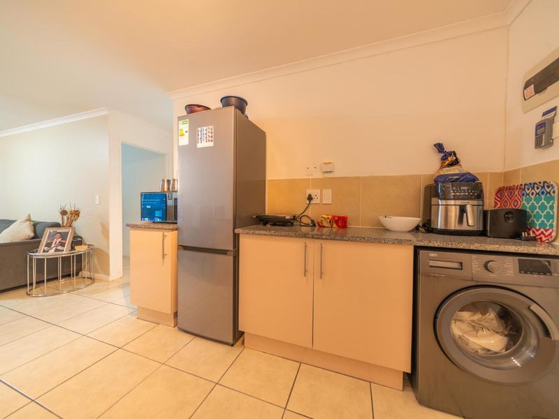 Compact kitchen area featuring granite countertops, laminate cabinetry, tiled backsplash, and tiled flooring, seamlessly integrated into the open-plan living space.