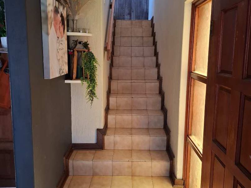 Entrance area featuring a tiled staircase with a wooden handrail and a large glass-paneled wooden door.