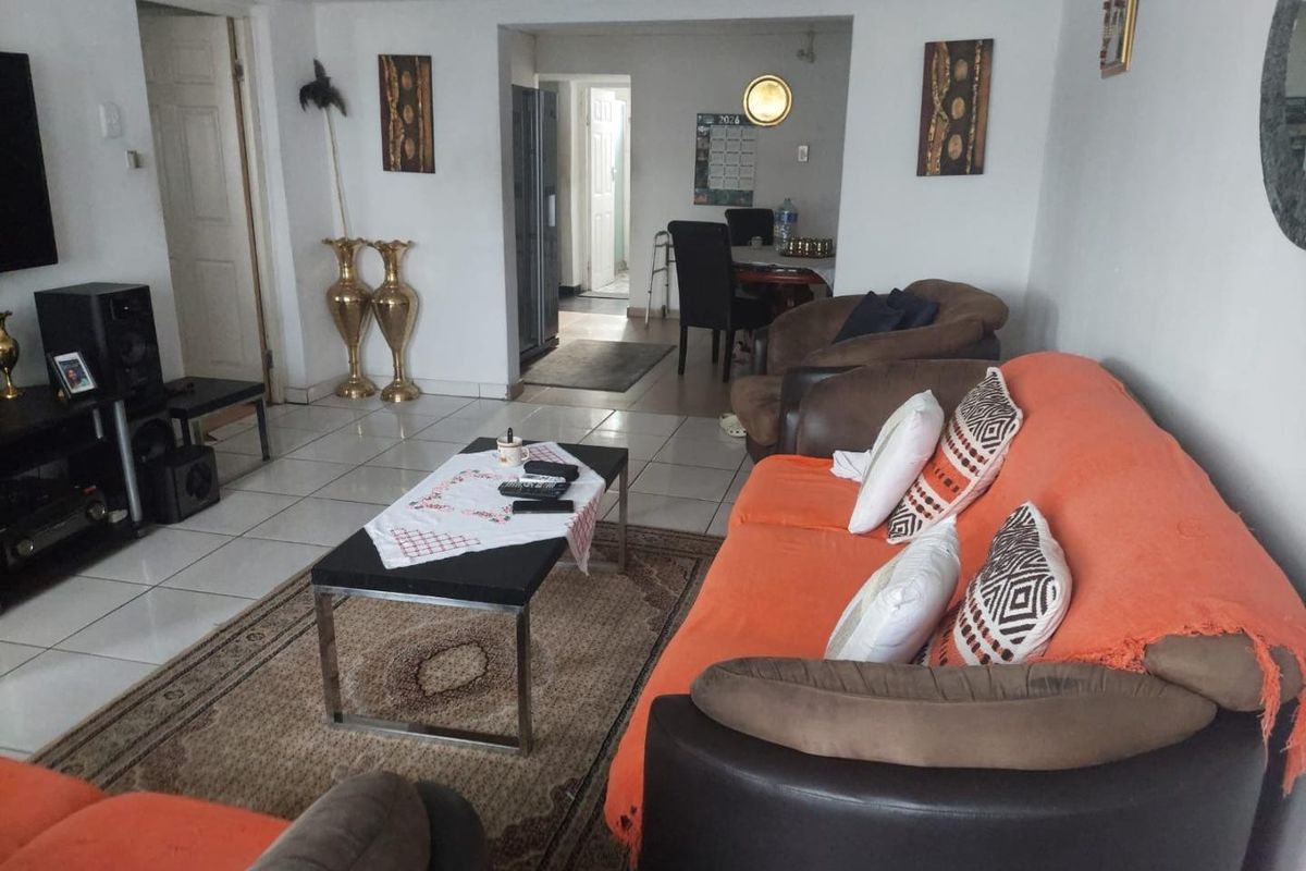 A living room area featuring tiled flooring and an open-plan layout leading to an adjacent dining space.
