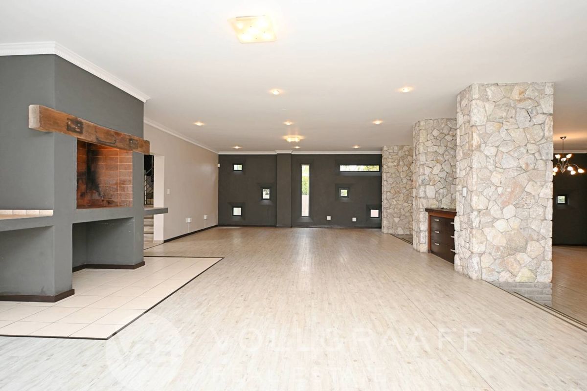 Spacious open-plan living area featuring a prominent built-in fireplace with a timber mantelpiece and decorative stone-clad pillars.