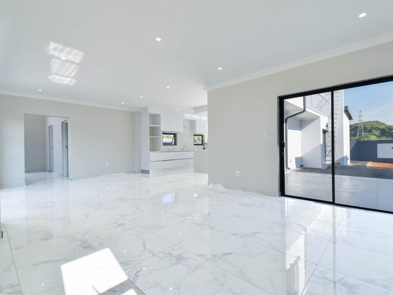 Spacious open-plan living area featuring polished marble-look floor tiles, recessed lighting, and large sliding glass doors providing seamless access to the outdoor patio.