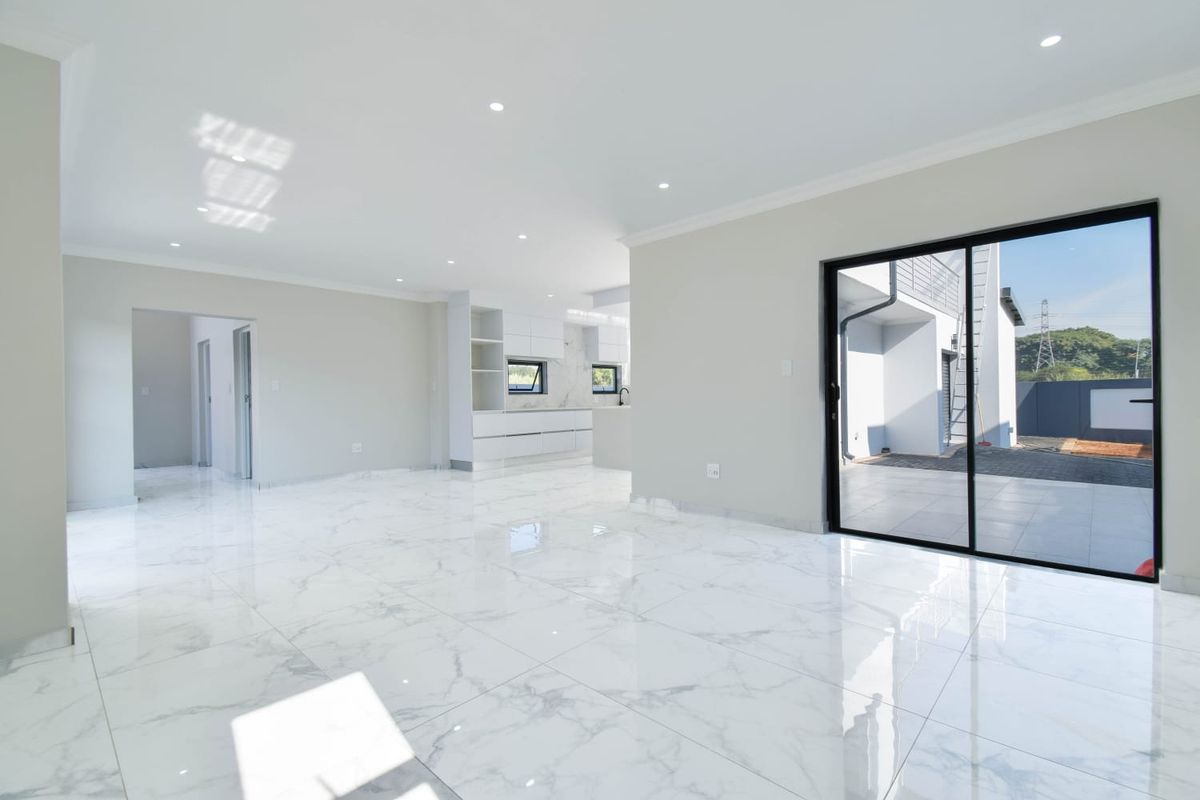 Spacious open-plan living area featuring polished marble-look floor tiles, recessed lighting, and large sliding glass doors providing seamless access to the outdoor patio.