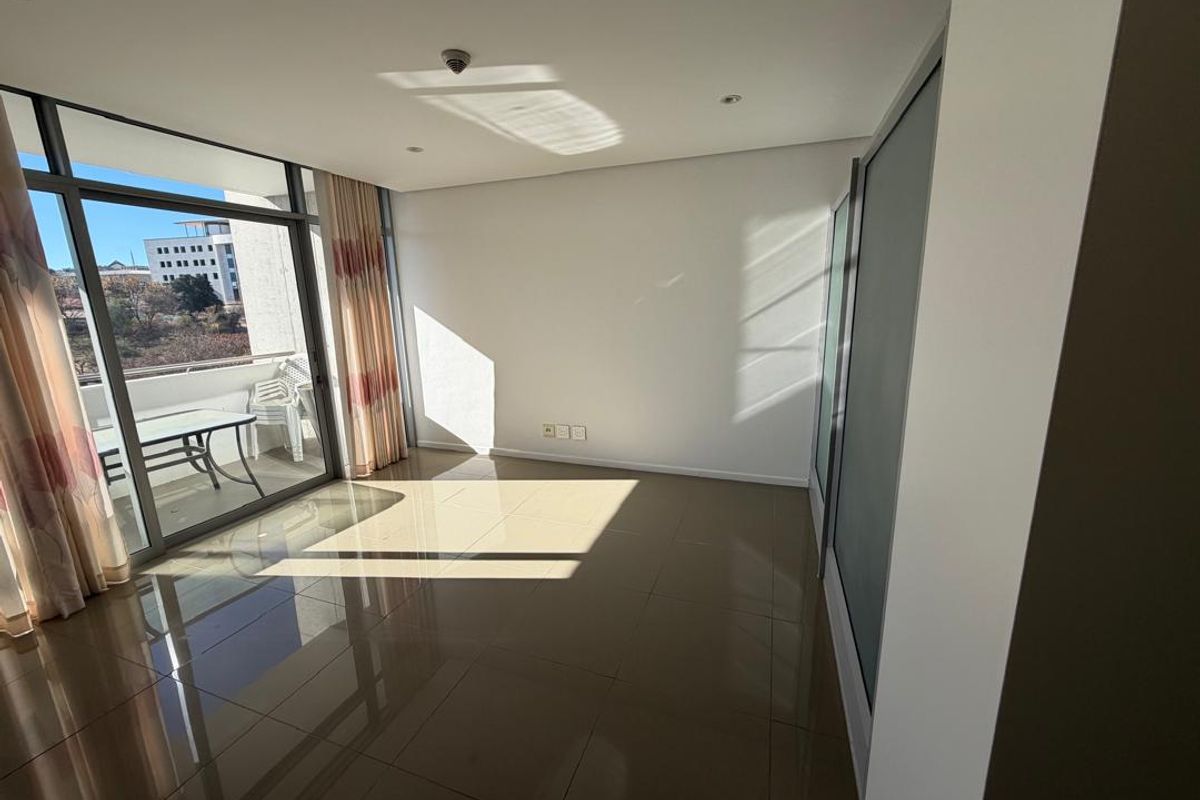 A bright, empty living area featuring polished tile flooring, built-in storage, and large sliding glass doors leading to an outdoor balcony.