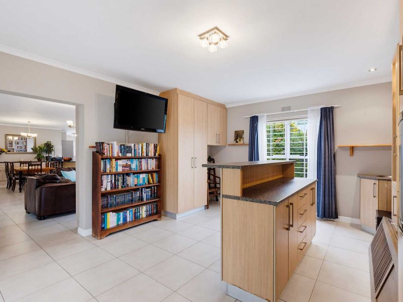 Open plan living area featuring tiled flooring, built-in cabinetry, and a central kitchen island with laminate countertops, flowing into the adjacent dining space.
