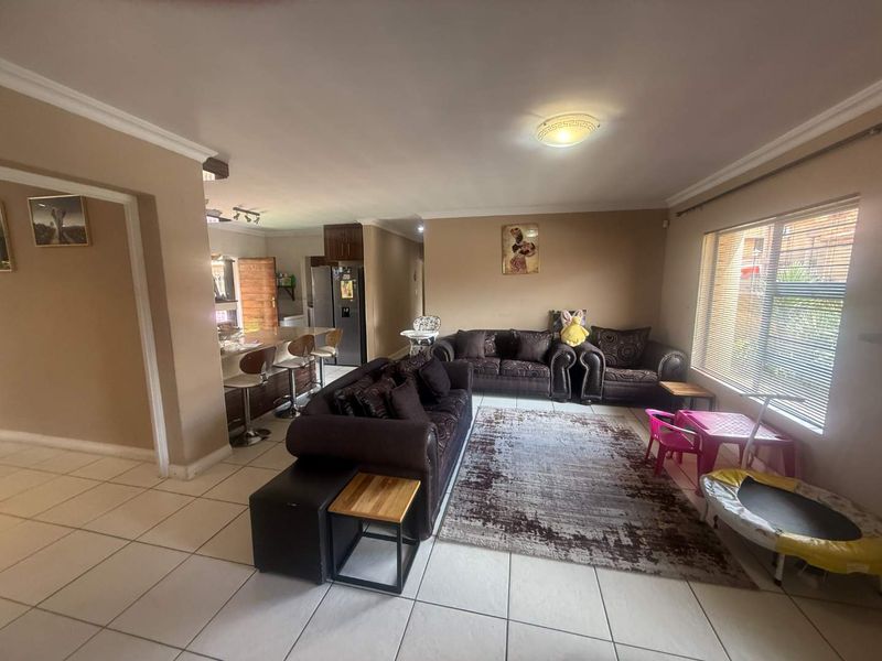 Spacious open-plan living area featuring tiled flooring, a breakfast counter, and a functional kitchen layout with ample natural light.
