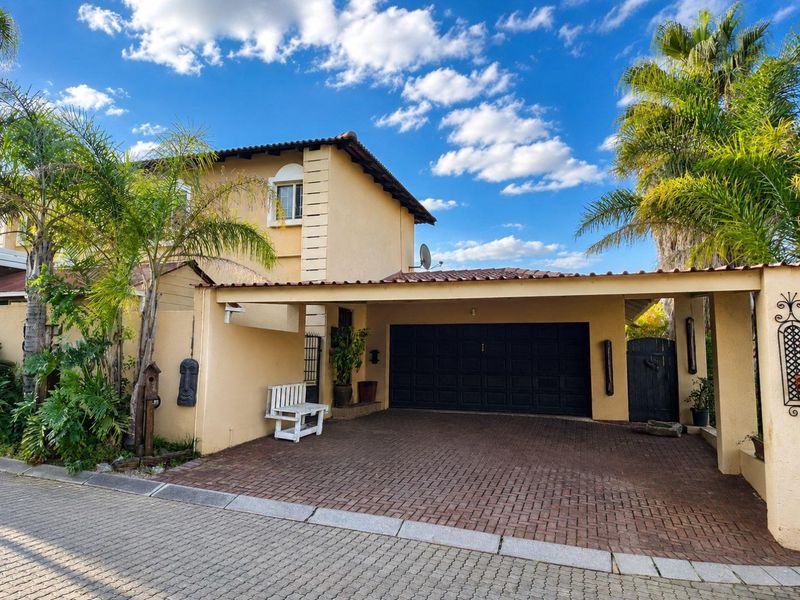 Front elevation of a two-story house featuring a paved driveway, integrated carport, and a secure garage entrance.