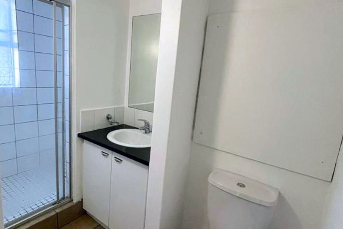 A functional bathroom featuring a shower enclosure, a vanity with a basin, and a standard toilet, finished with tiled flooring.