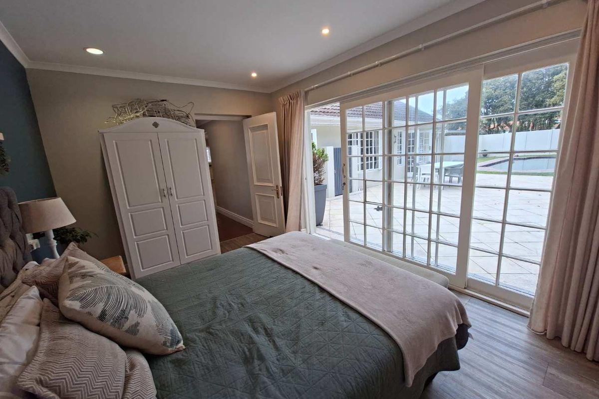 Spacious bedroom featuring laminate flooring, recessed lighting, and large sliding glass doors providing direct access to the outdoor patio and pool area.