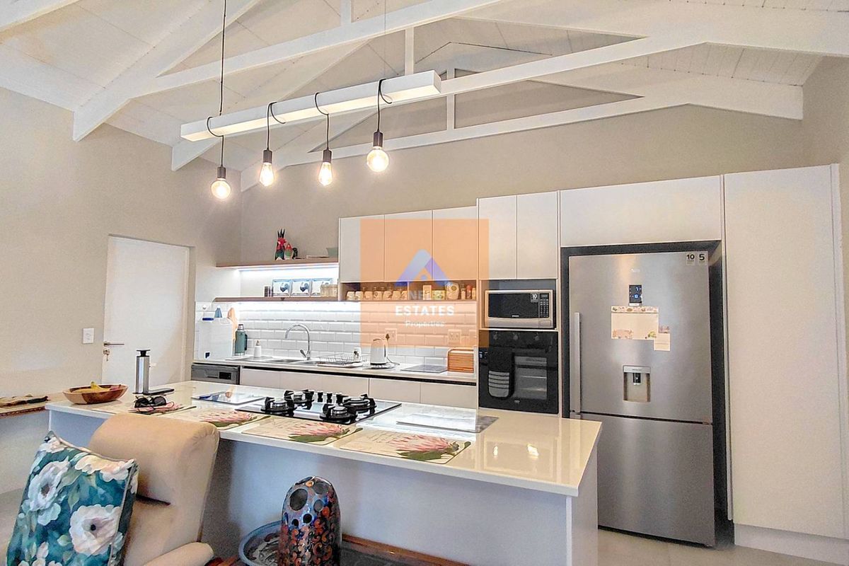 Modern kitchen featuring white cabinetry, stone countertops, subway tile backsplash, gas hob, built-in oven, and high vaulted ceilings with exposed rafters.