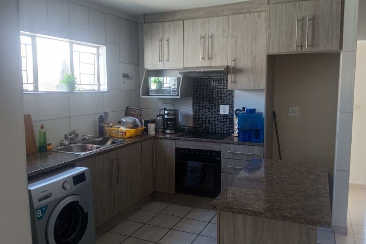 Functional kitchen featuring wood-look cabinetry, granite countertops, mosaic tile backsplash, built-in oven, extractor fan, and space for a washing machine.