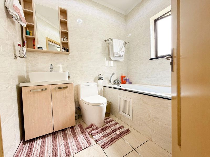 A well-maintained bathroom featuring a vanity with vessel sink, a toilet, and a bathtub with tiled finishes throughout.