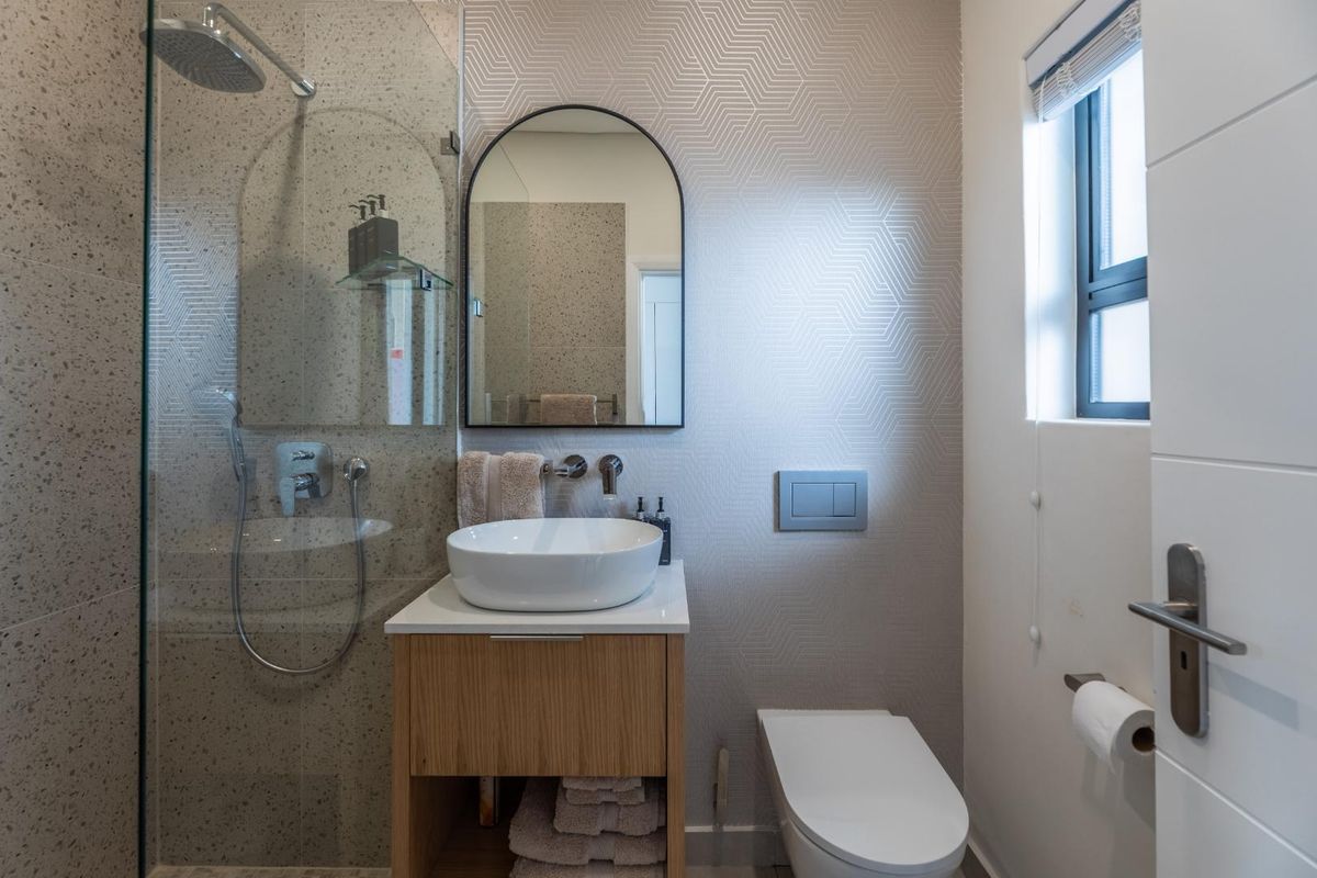 Modern bathroom featuring a walk-in shower with terrazzo-style tiling, a wall-hung vanity with vessel basin, and a wall-hung toilet with concealed cistern.