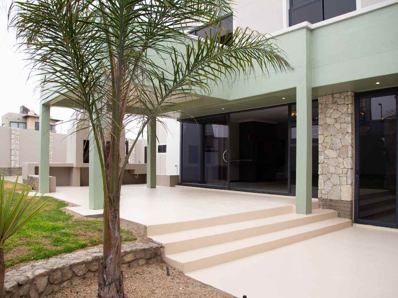 A spacious covered patio featuring stone cladding, recessed lighting, and direct access to the interior through large sliding glass doors.