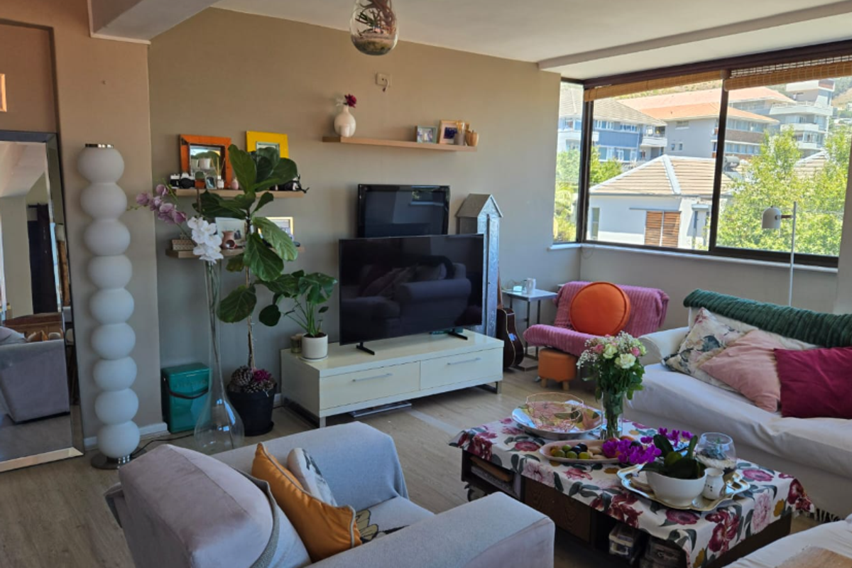 A bright living room featuring large windows with neighborhood views, neutral wall tones, and durable laminate flooring.