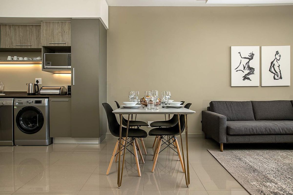 Modern open-plan living area featuring a compact kitchen with built-in cabinetry, integrated appliances, and sleek tiled flooring throughout the space.