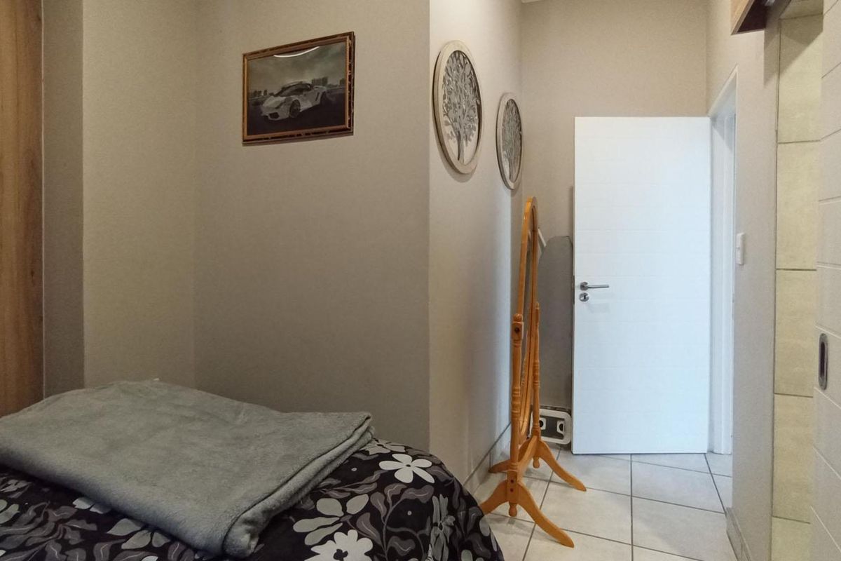 A bedroom featuring tiled flooring and a built-in wooden wardrobe, providing a clean and functional living space.