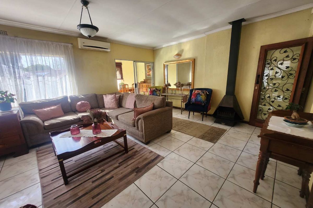 Spacious living room featuring a built-in fireplace, split-system air conditioning, and tiled flooring with direct access to an adjoining room.