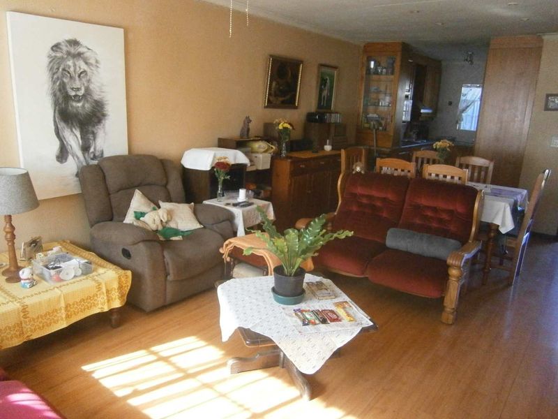 Open plan living and dining area featuring laminate flooring, flowing into a kitchen space with built-in cabinetry.