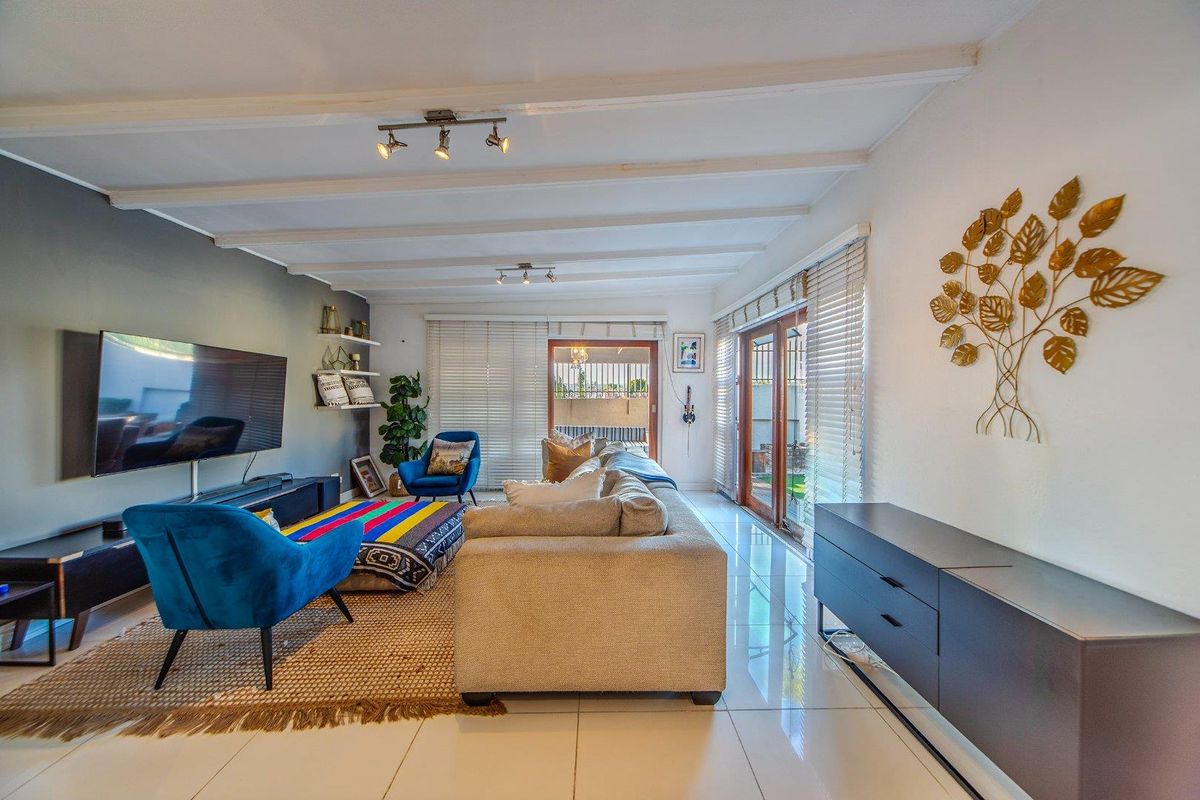Spacious living room featuring tiled flooring, exposed beam ceilings, and large sliding glass doors that provide ample natural light and access to the outdoors.