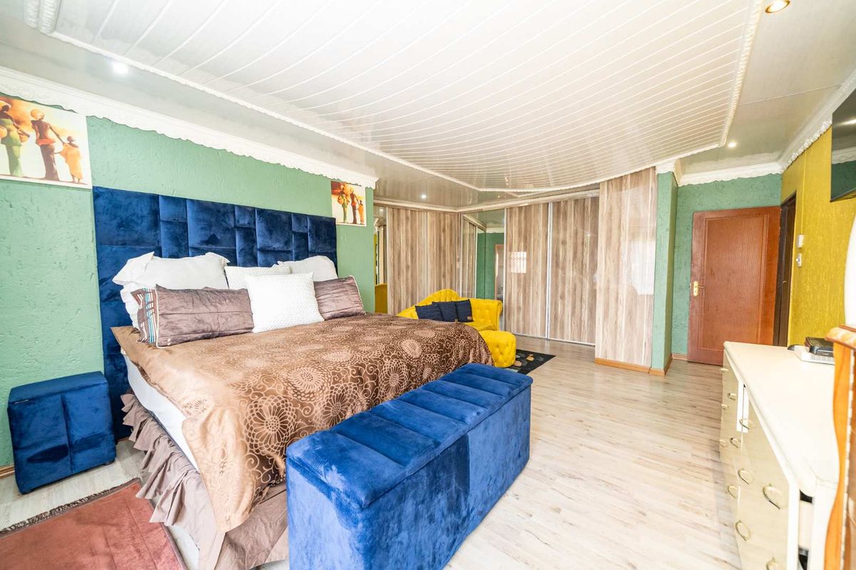 Spacious bedroom featuring built-in wooden wardrobes, laminate flooring, and a decorative ceiling with integrated lighting.
