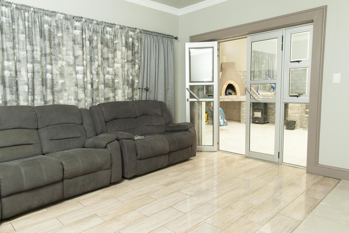 Living room featuring tiled flooring and large glass doors opening onto a covered patio area with a built-in pizza oven.