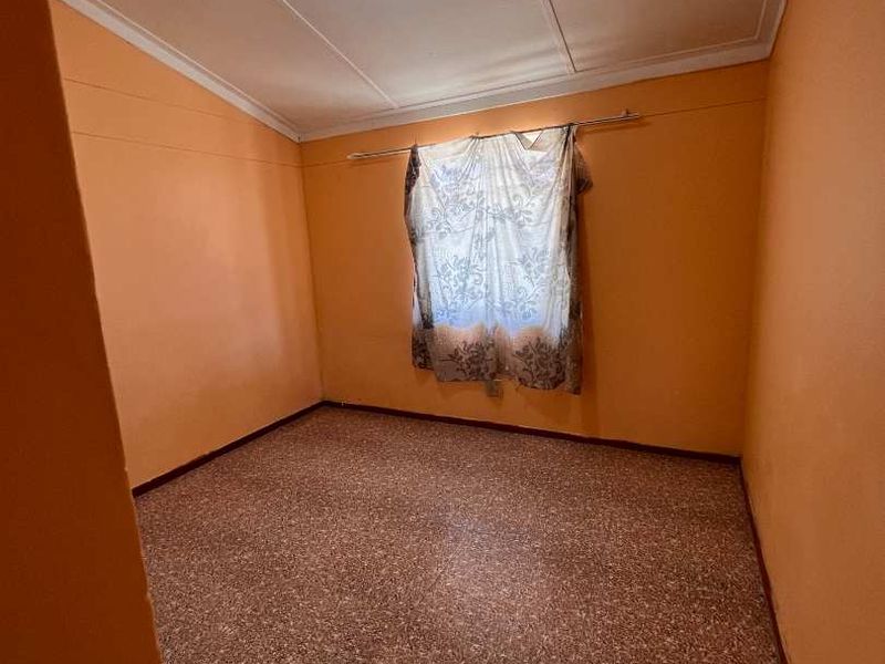 An empty bedroom featuring terrazzo flooring, orange painted walls, and a central ceiling light fixture.