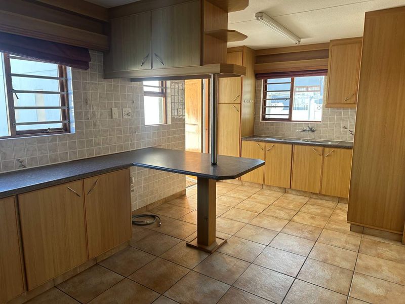 A functional kitchen featuring laminate cabinetry, tiled backsplash, and a breakfast bar, offering a clean, dated space ready for modernization.