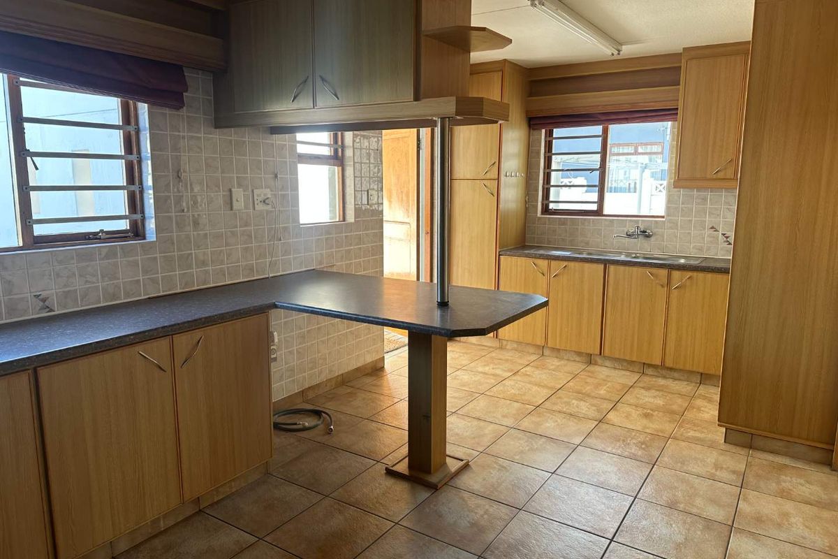 A functional kitchen featuring laminate cabinetry, tiled backsplash, and a breakfast bar, offering a clean, dated space ready for modernization.