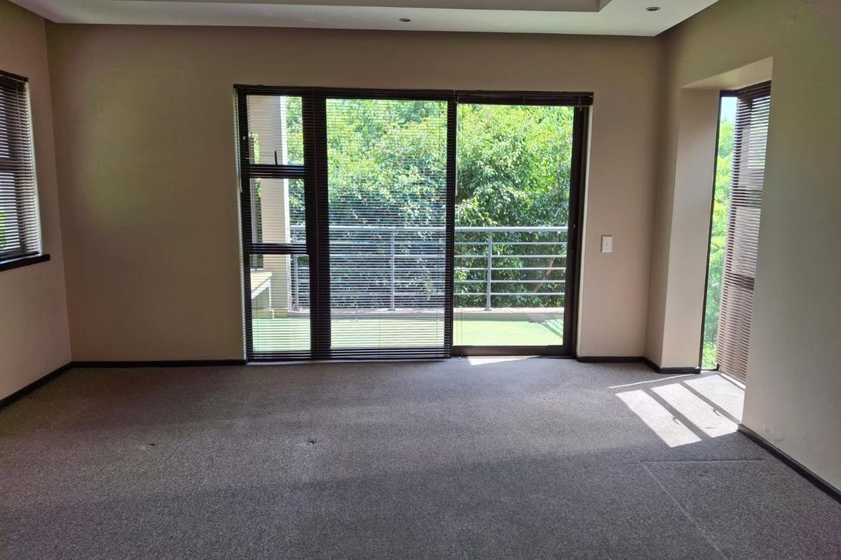 Spacious, empty living area featuring neutral carpeting, recessed ceiling detail, and large sliding glass doors providing access to an outdoor balcony.