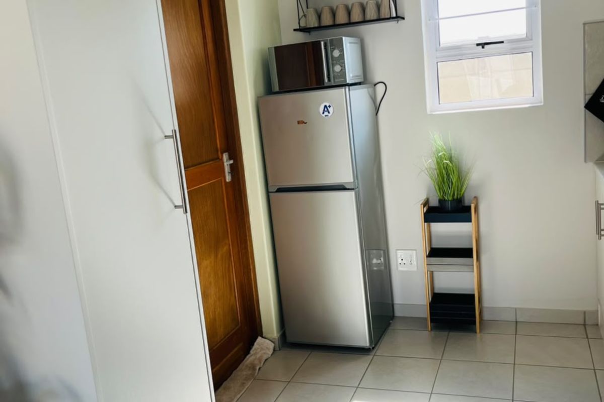 A functional kitchen area featuring tiled flooring, a timber door, and a window, providing a clean and practical space.