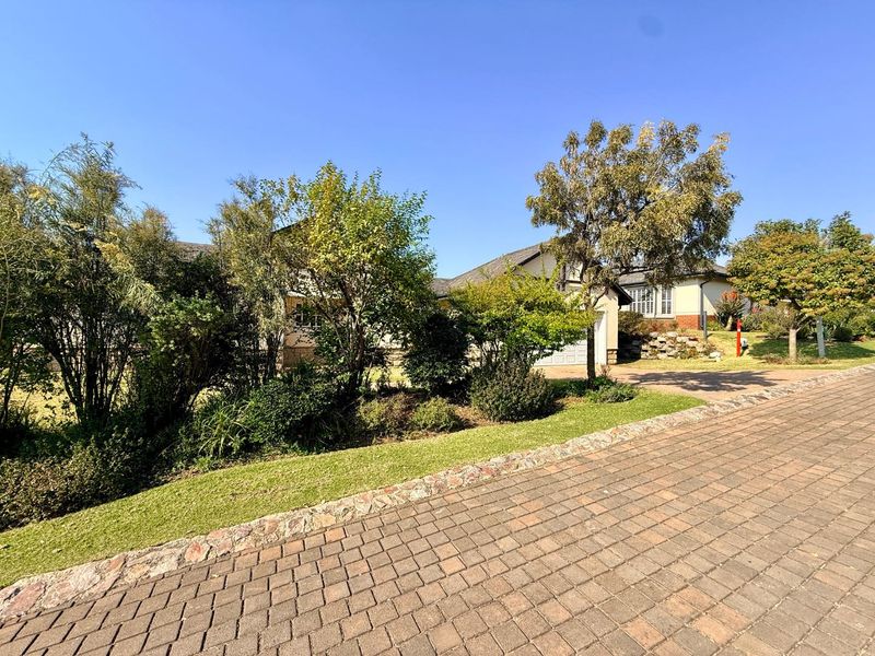 A view of the front exterior of the house, featuring a paved driveway, landscaped garden, and a garage.