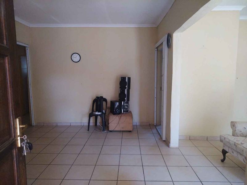 A sparsely furnished living area featuring neutral tiled flooring and coved ceilings, offering a blank canvas for interior design updates.