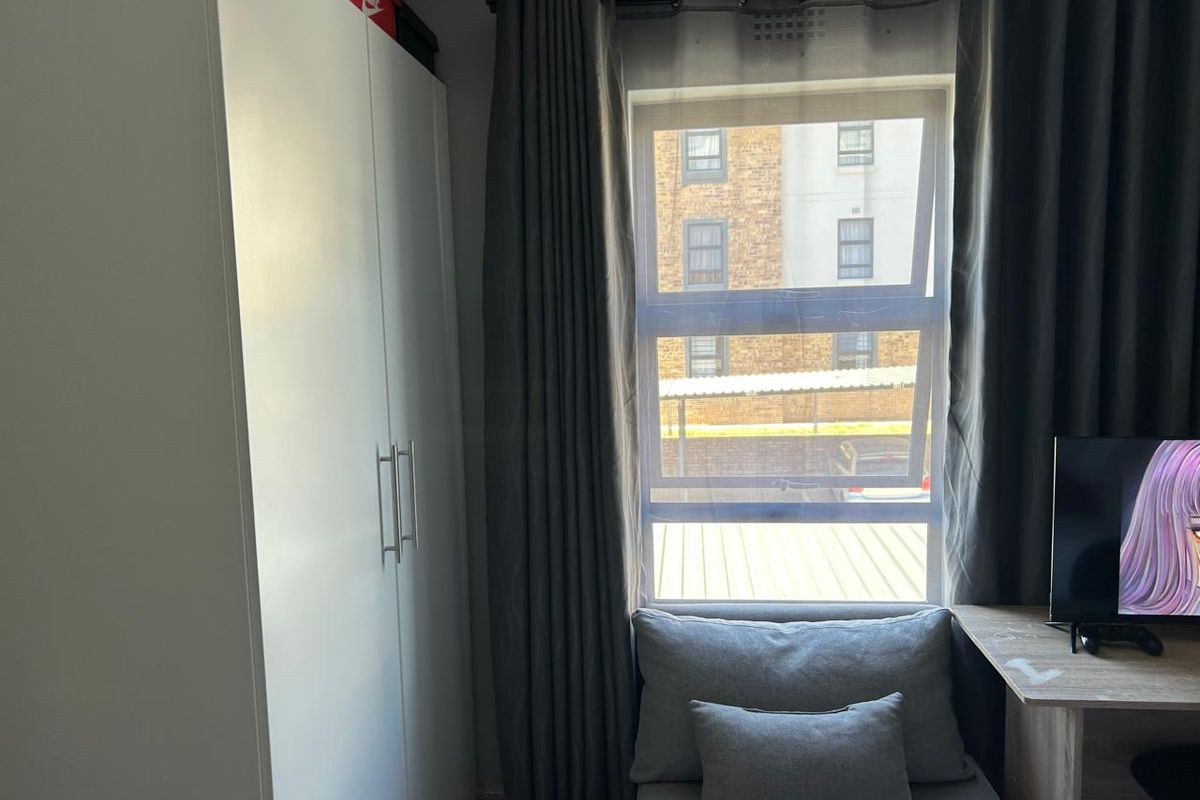 A bedroom featuring a built-in wardrobe and a window with views of the surrounding apartment complex.