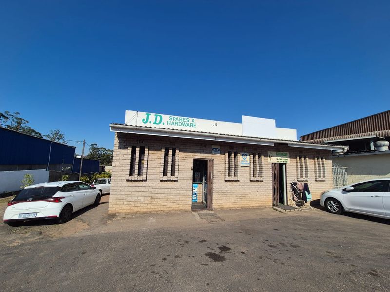 Front elevation of a commercial brick building featuring security bars and a paved driveway area.
