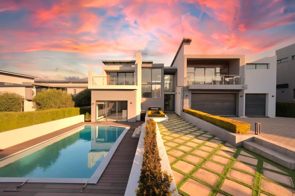 Modern luxury residence featuring a swimming pool, timber decking, paved garden pathways, and double garage with contemporary architectural design.