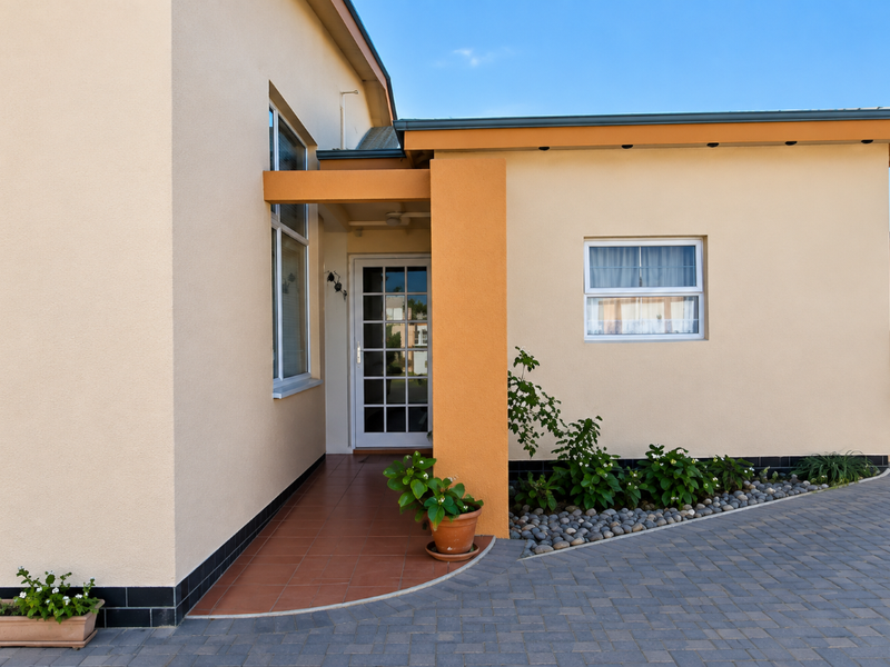 A well-maintained front entrance featuring a tiled porch, paved driveway, and clean exterior facade with modern window finishes.
