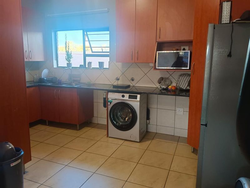 Functional kitchen featuring laminate cabinetry, granite countertops, tiled backsplash, and dedicated space for laundry appliances under the counter.