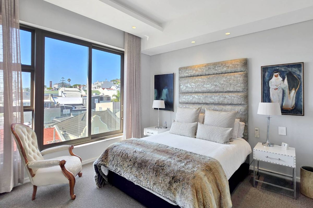 A well-maintained bedroom featuring a large window with city views, recessed ceiling lighting, and a custom built-in headboard.