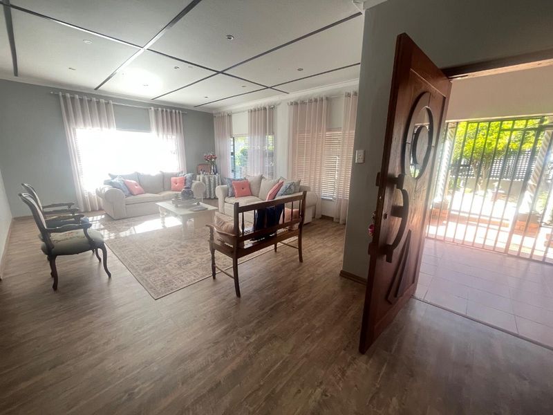 Spacious living room featuring laminate flooring, recessed ceiling lighting, and a solid timber front door with an integrated security gate.