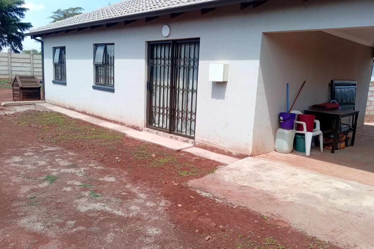 Rear view of the house featuring a covered patio area, sliding glass doors with security gates, and tiled roof.