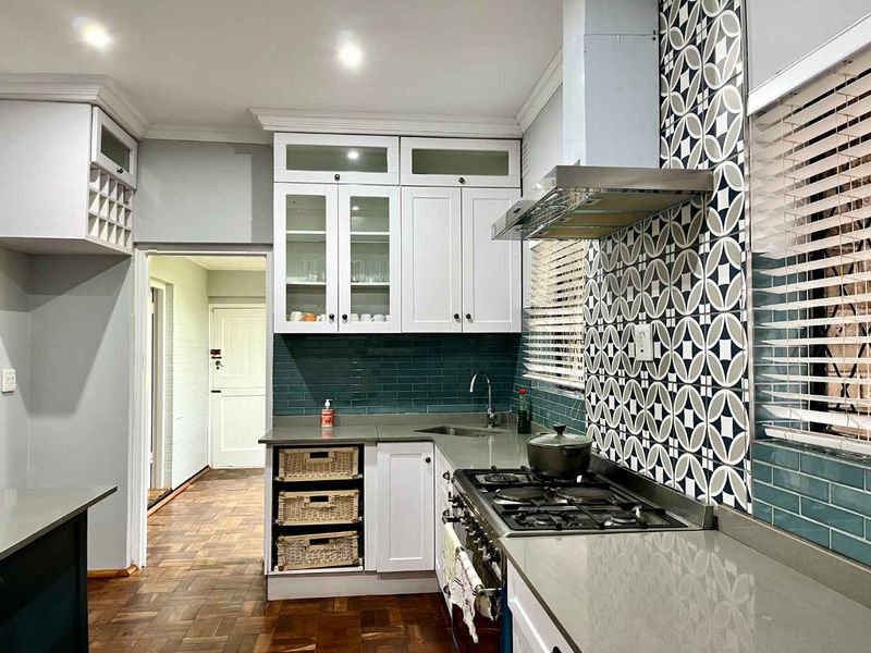 Modern kitchen featuring white cabinetry, stone countertops, a gas stove with extractor fan, and stylish subway and patterned tile backsplashes.