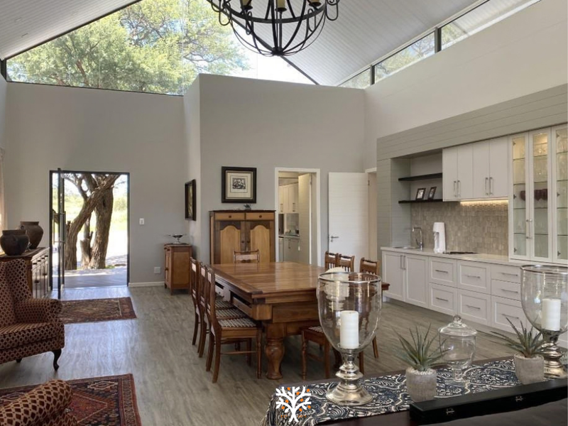 Spacious open-plan living and dining area featuring a high vaulted ceiling, clerestory windows for natural light, and a modern built-in kitchen cabinetry unit.