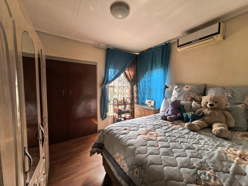 A bedroom featuring laminate flooring, a built-in wardrobe, and a wall-mounted split-system air conditioner.