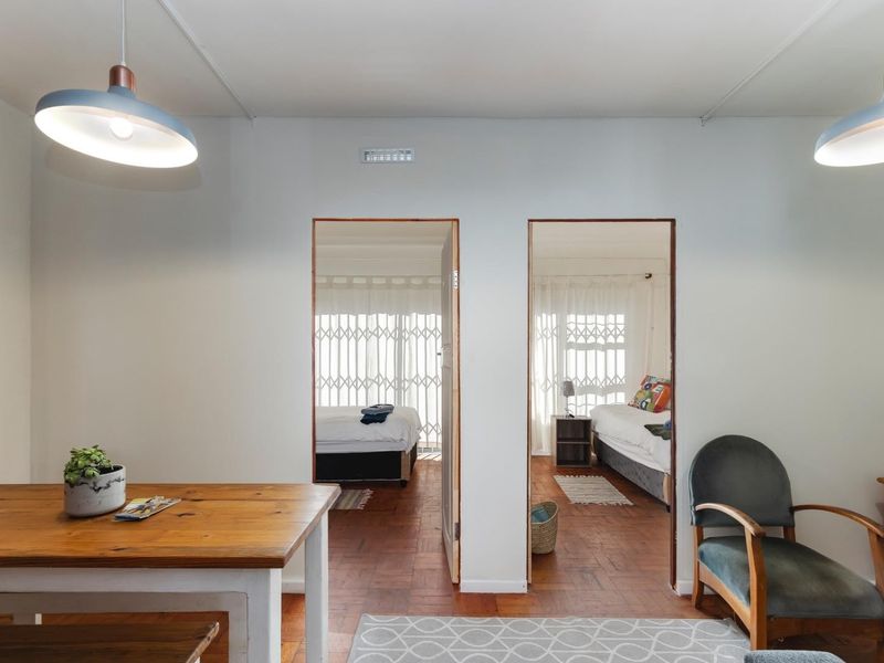 Living area featuring classic parquet flooring and dual pendant lights, providing direct access to two separate bedrooms through central doorways.
