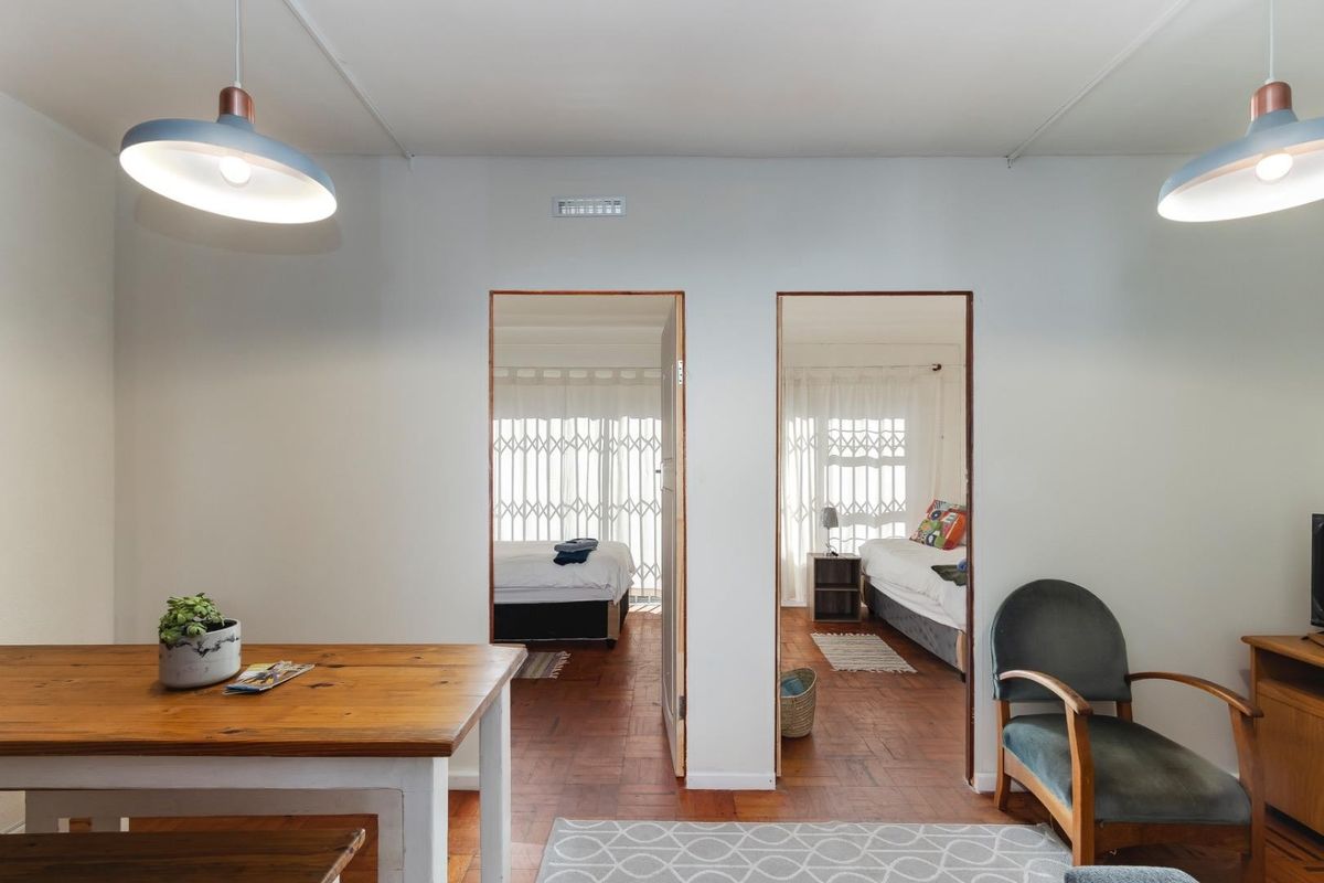 Living area featuring classic parquet flooring and dual pendant lights, providing direct access to two separate bedrooms through central doorways.